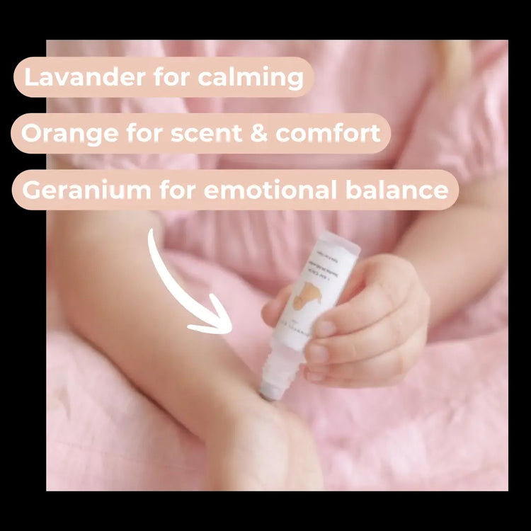 Baby holding a bottle with text about essential oils on a pink background