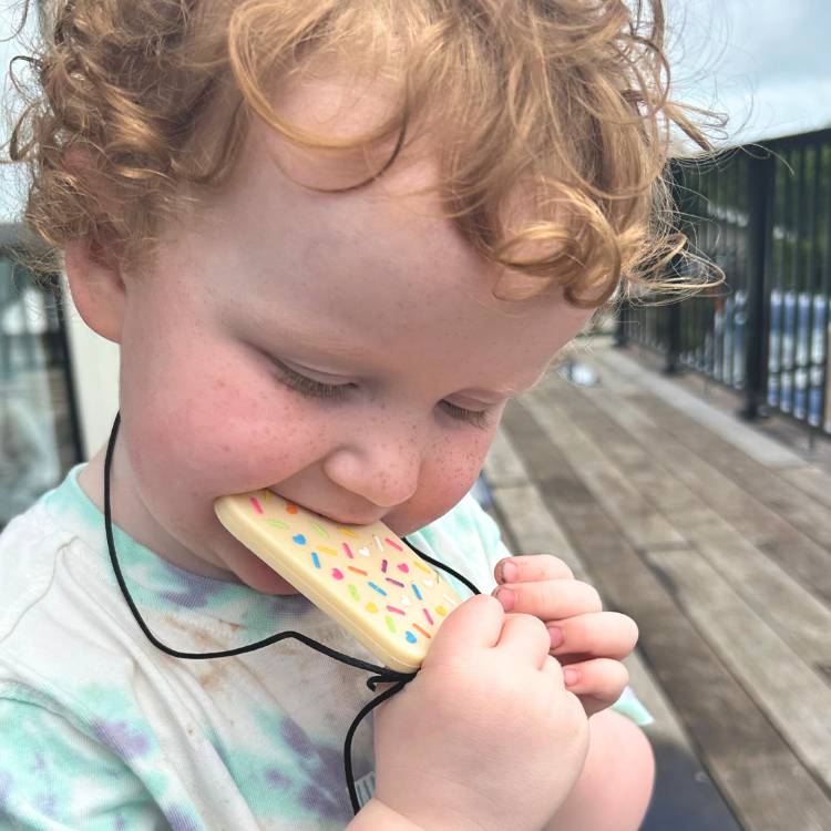 Child holding a toy phone with colorful buttons outdoors