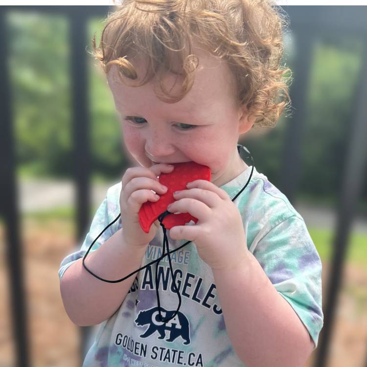 Child playing with a red toy outdoors