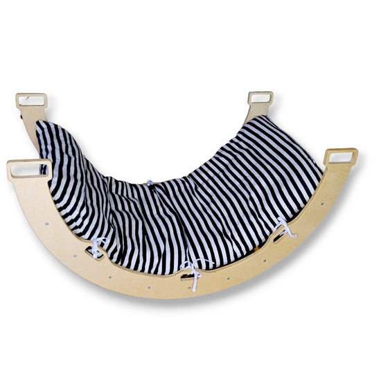 A black and white striped cushion placed on a beige-colored wooden rocking archer meant for children.
