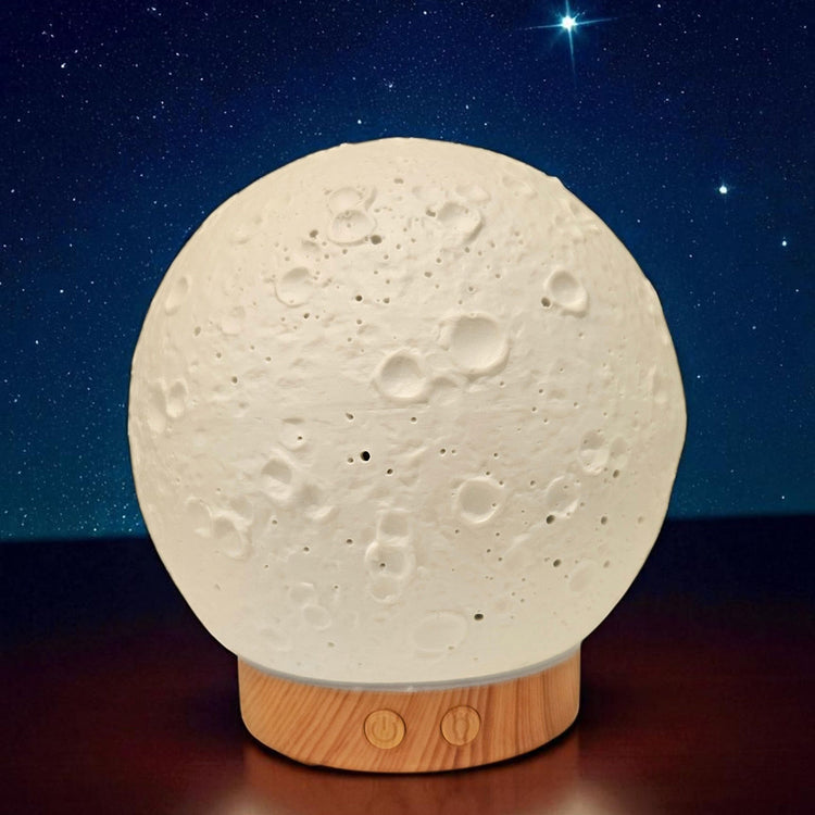 Moon-shaped lamp with wooden base against a starry night sky