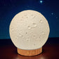 Moon-shaped lamp with wooden base against a starry night sky