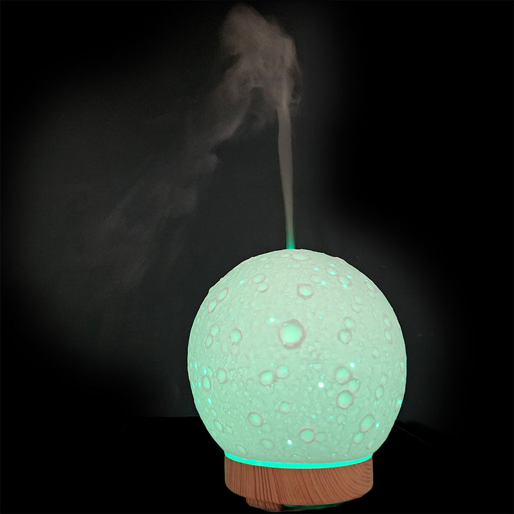 Moon-shaped humidifier emitting mist on a dark background