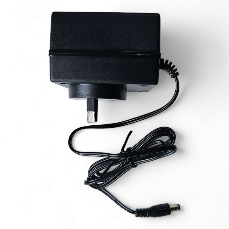 Black wall plug power adapter with coiled cable and barrel connector.
