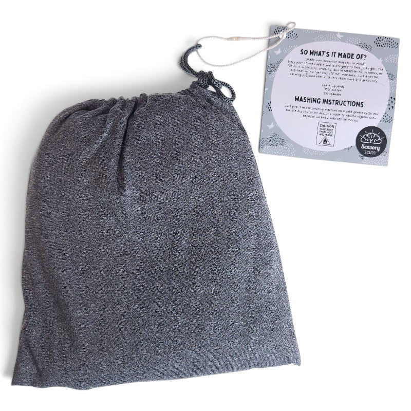 Grey Cuddle Pod drawstring storage bag shown beside its Sensory Sam care instruction tag.