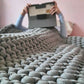 Person holding a tablet under a textured blanket on a bed