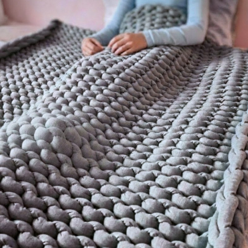Cozy gray textured blanket draped over a surface with a person partially visible.