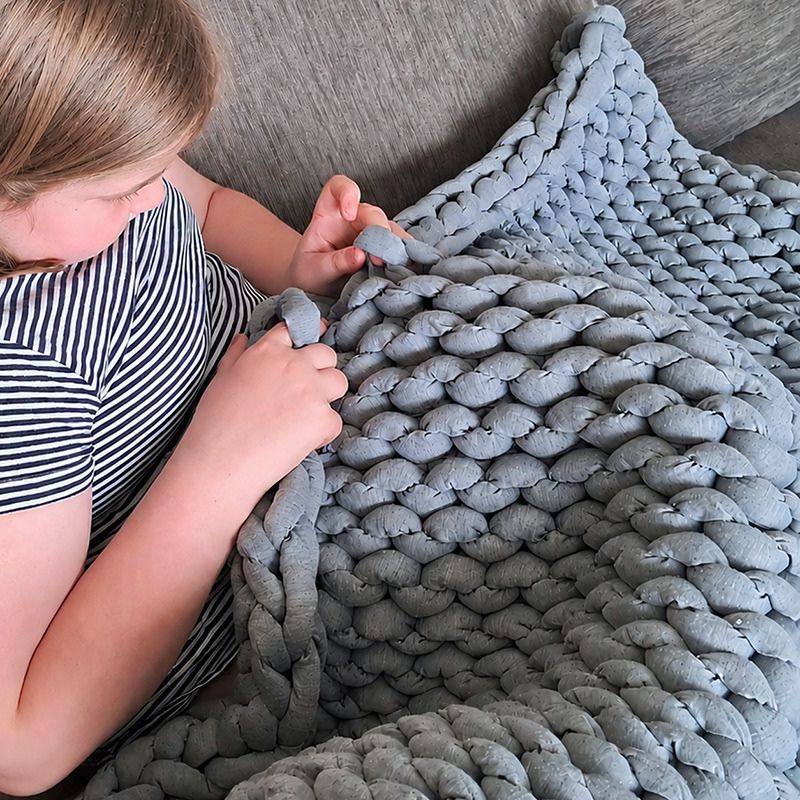 Child playing with a textured gray blanket on a couch