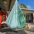 Person in a green hammock outside a building with red shelves.