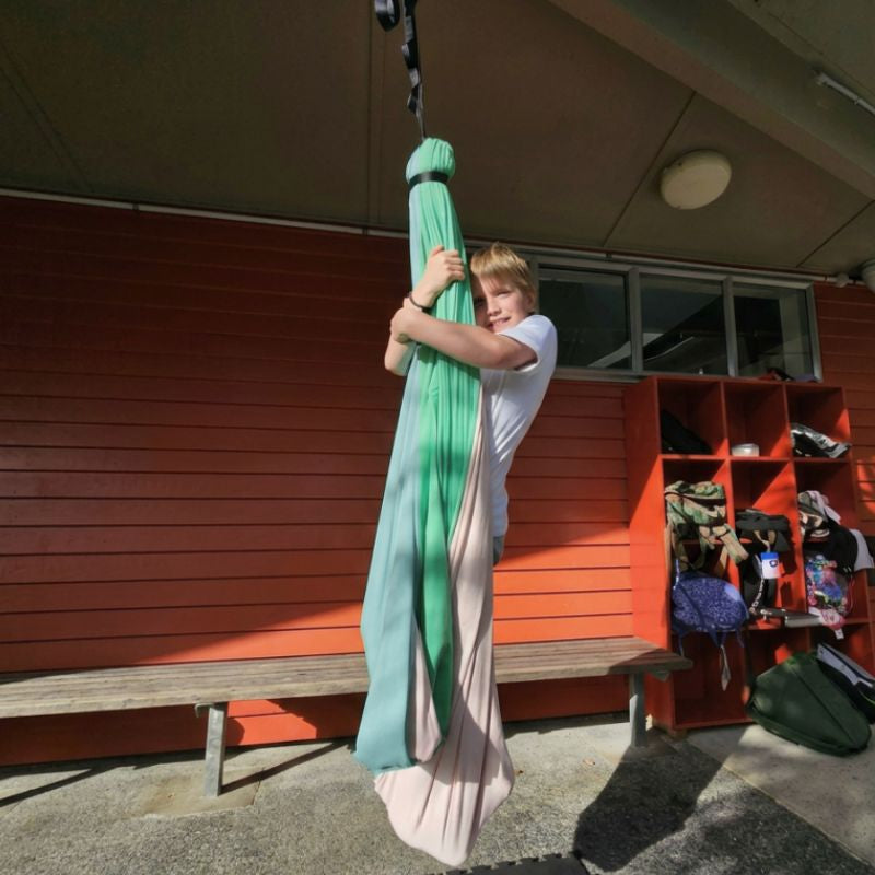 Person holding a colorful hammock in front of a building with shelves.