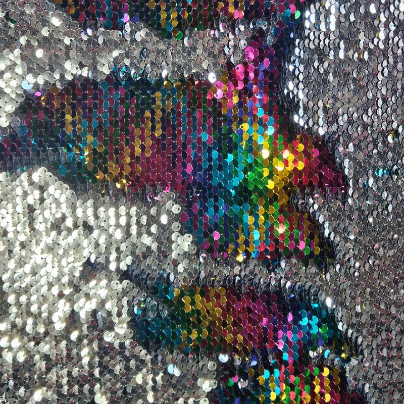 Close-up of a sequined fabric with a colorful pattern on a silver background