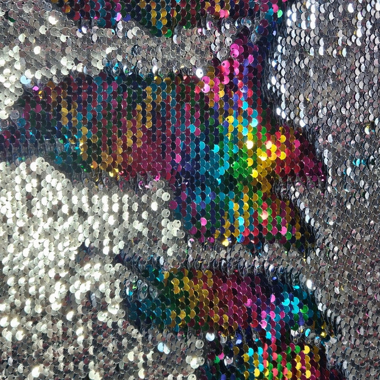 Close-up of a sequined fabric with a colorful pattern on a silver background