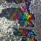Close-up of a sequined fabric with a colorful pattern on a silver background