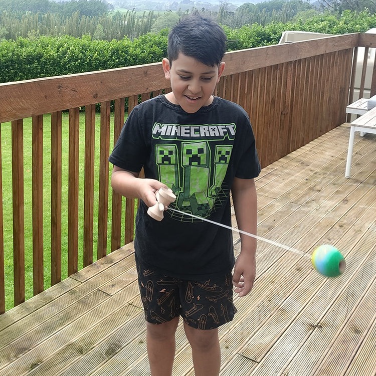 Child playing with a ball on a wooden deck