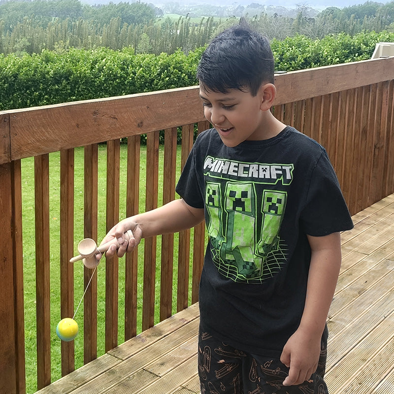 Child wearing a Minecraft shirt on a wooden deck with greenery in the background