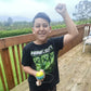 Child wearing a Minecraft shirt, holding a colorful ball on a wooden deck with greenery in the background