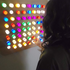 A person interacting with a multicolored LED acrylic light wall, with lights in various colors illuminated in a pattern.