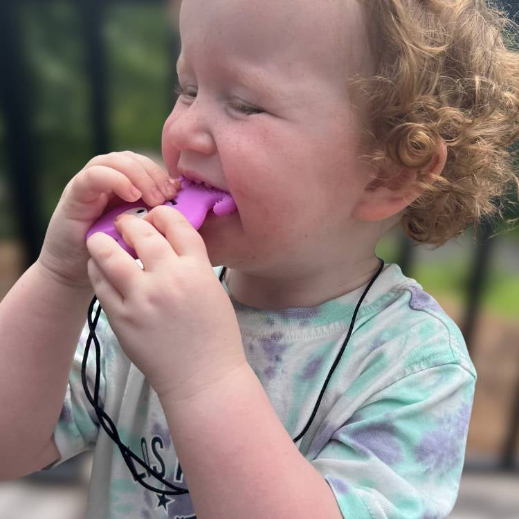 Child playing with a purple toy outdoors