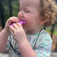 Child playing with a purple toy outdoors
