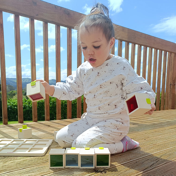 Child playing with building blocks on a wooden deck with a scenic background