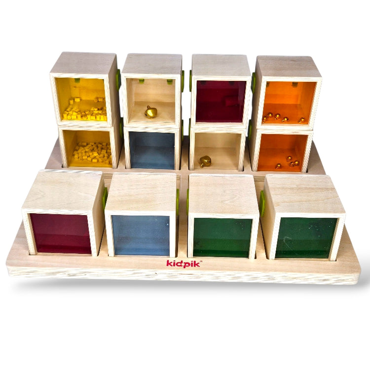 Colorful wooden cube puzzle with transparent sides, each containing small objects, on a white background. Brand &