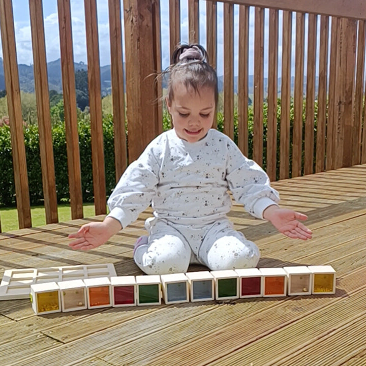 Child sitting on a wooden deck with a color sorting toy
