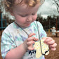 Child holding a toy resembling a donut with sprinkles outdoors
