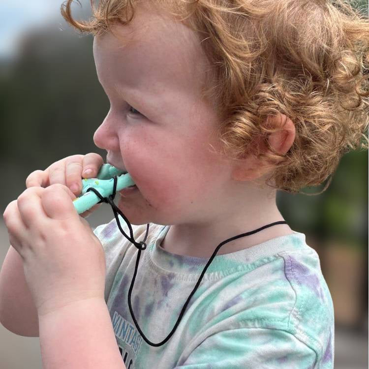 Child with curly hair holding a turquoise object outdoors