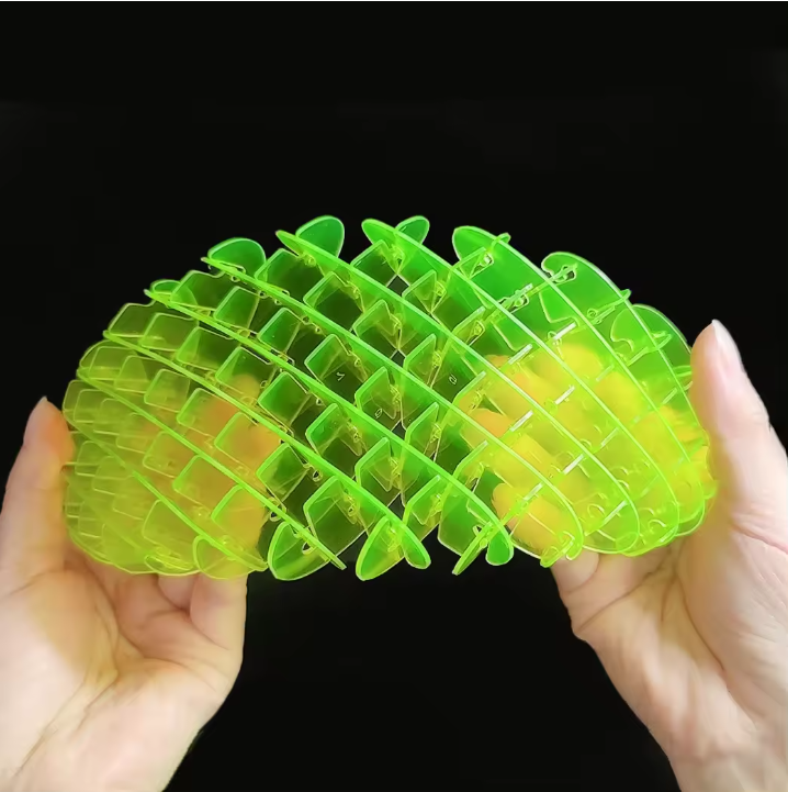 Green plastic tool held between two hands against a black background