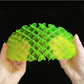Green plastic tool held between two hands against a black background