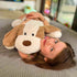 A child lying on a couch hugging a lifelike weighted dog toy that is brown and white in color, resembling a puppy.