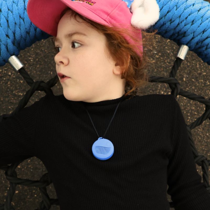 Child wearing a pink helmet with a blue tag, sitting in a stroller.