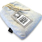 A grey sensory bed sheet made of cotton and spandex with a label attached showing the brand and product name.