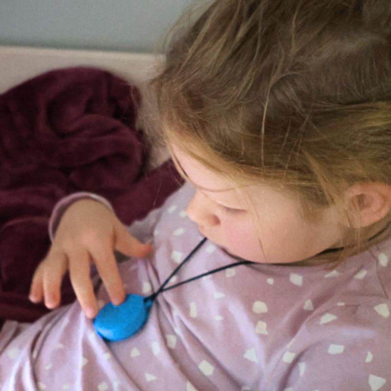 Child playing with a blue toy on a pink blanket