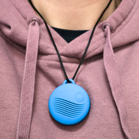 Blue pendant necklace on a person wearing a pink hoodie