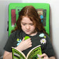 Child reading a Minecraft joke book with a green cushion featuring Minecraft characters in the background.
