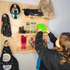 A child wearing headphones covering their ears, standing in front of a wooden pegboard with various colorful toys and sensory items.