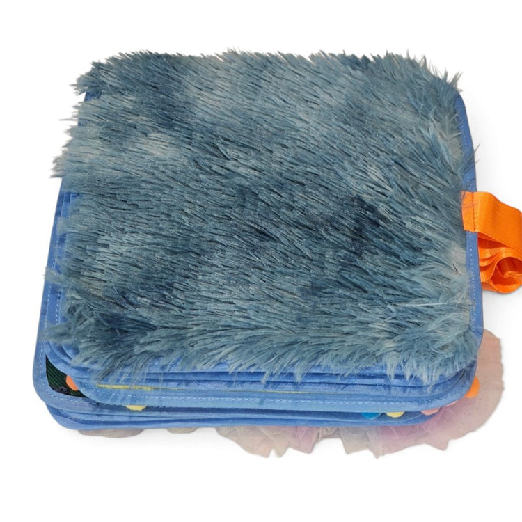 Texture Discovery Book closed, showing its blue faux fur cover, layered fabric pages and orange tab.