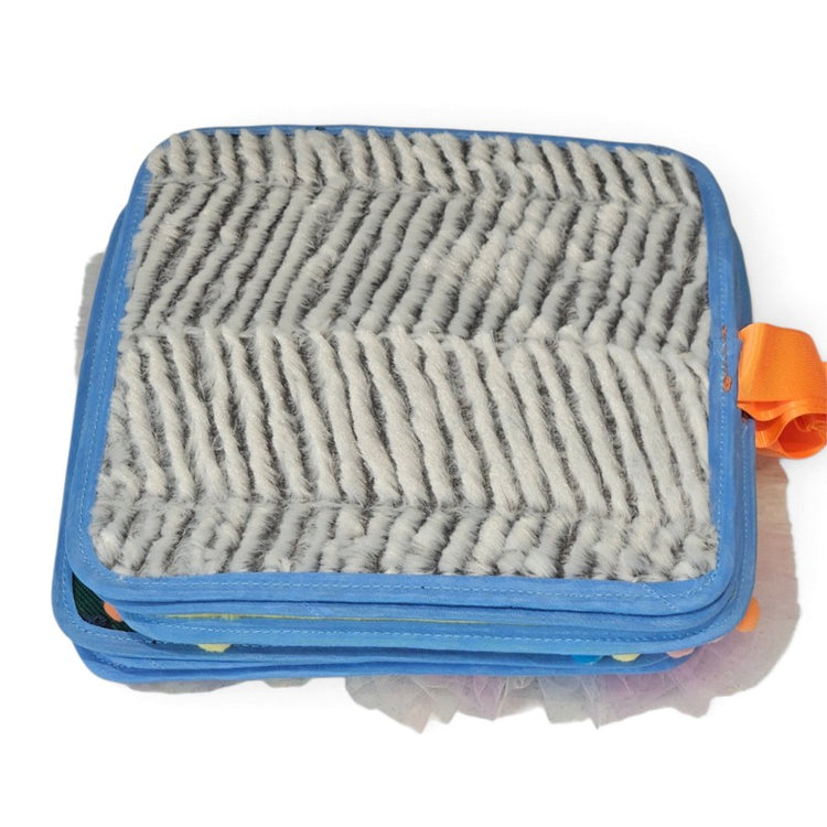 Texture Discovery Book closed, showing its grey striped plush cover, blue fabric edging and orange tab.