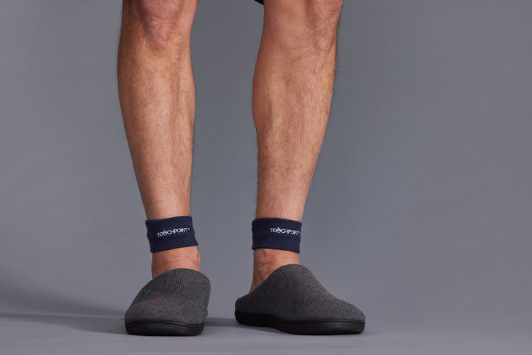 Person wearing navy socks with a brand logo on a gray background