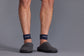 Person wearing navy socks with a brand logo on a gray background