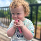 Child holding a pink object outdoors on a wooden deck