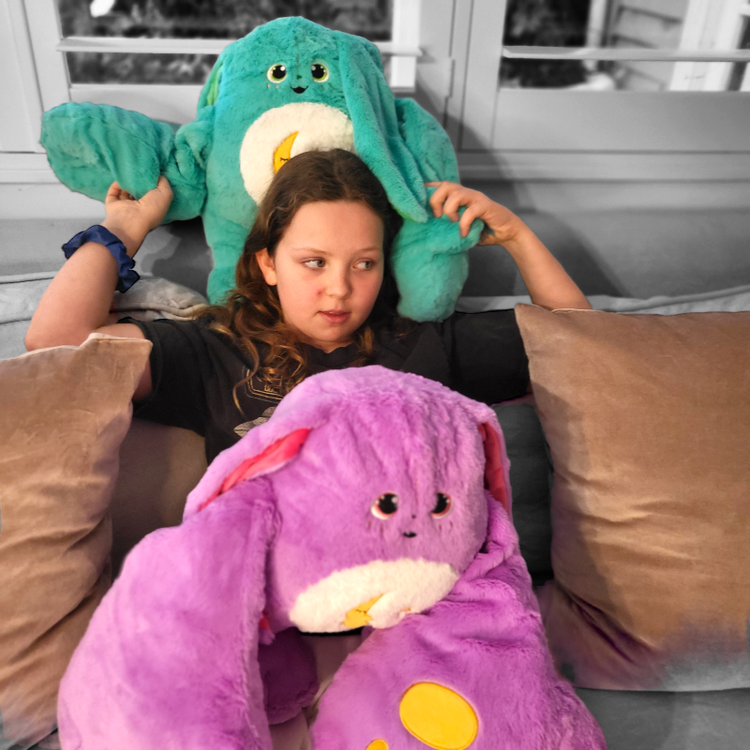 Child seated with green and purple weighted monster plush toys