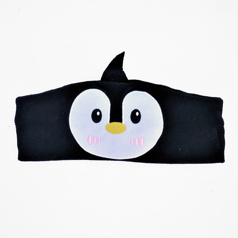 A child wearing a brown pair of ear muffs with a bear design on the top, connected to a device via a 3.5 mm cable.