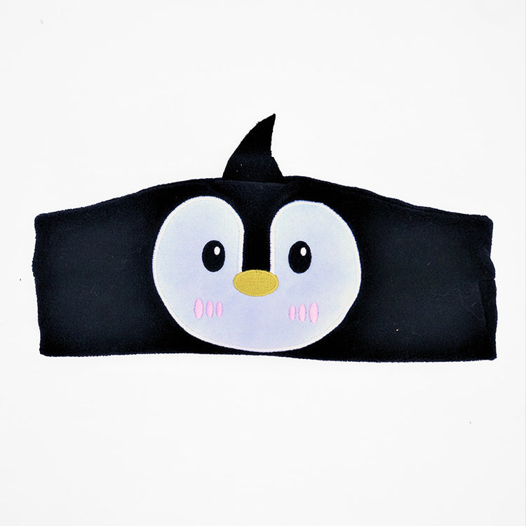 A child wearing a brown pair of ear muffs with a bear design on the top, connected to a device via a 3.5 mm cable.