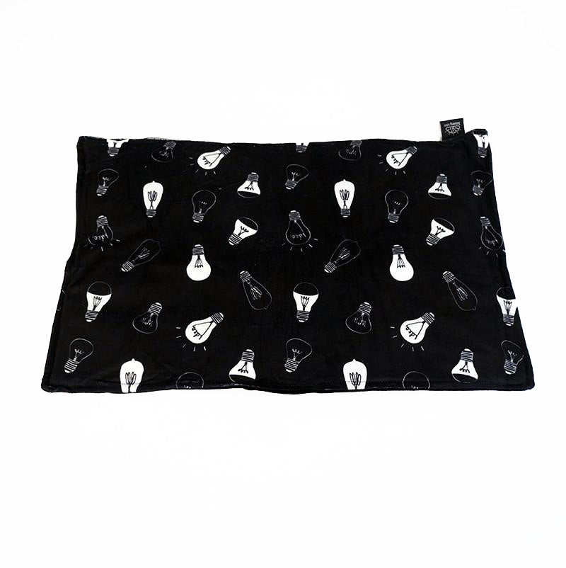 A black lap pad with a pattern of light bulb designs, laid flat.