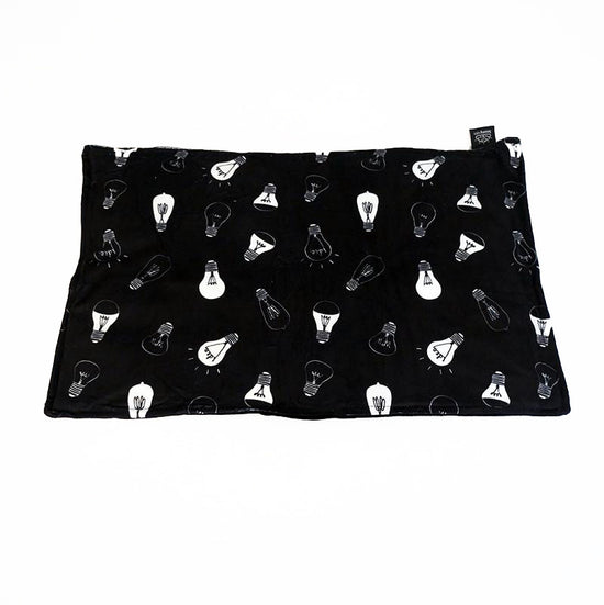 A black lap pad with a pattern of light bulb designs, laid flat.