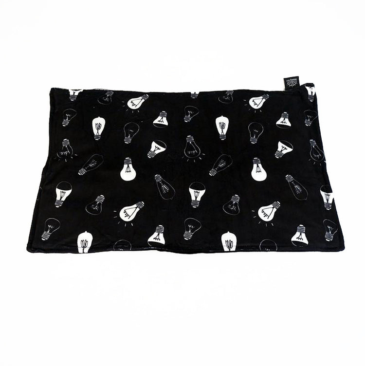 A black lap pad with a pattern of light bulb designs, laid flat.