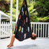A child is seen enjoying a black sensory swing with colorful geometric patterns, hanging outdoors.