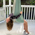A child enjoying a sensory swing made of double layered cotton spandex in a duck egg blue color, hanging outdoors.